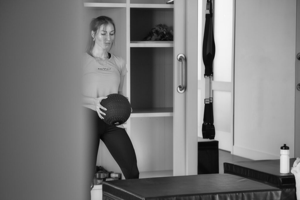 Woman in sportswear is holding a med ball at the gym.